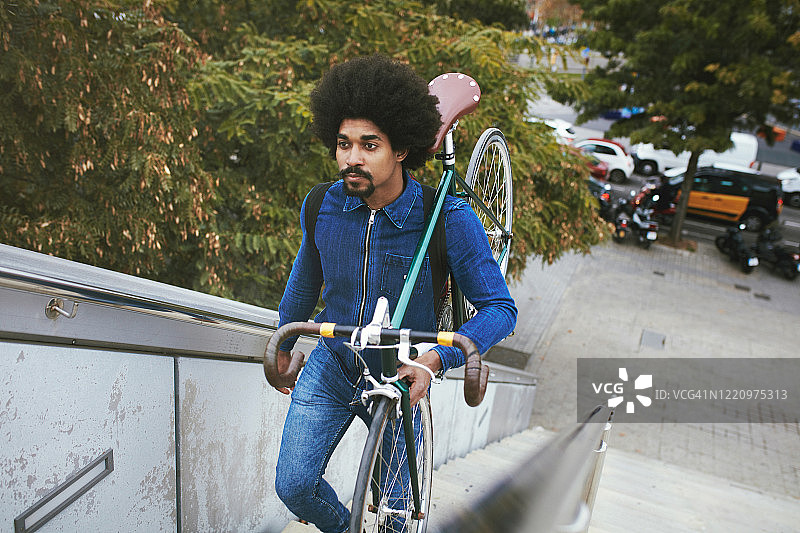 加勒比黑人男性通勤者携带自行车上楼图片素材