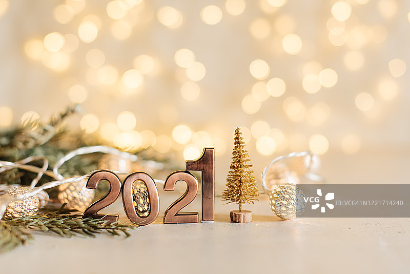 2021年新年快乐。金色数字2021与圣诞帽在黑色背景与散焦。假日派对装饰或明信片概念与顶视图和复制空间。图片素材