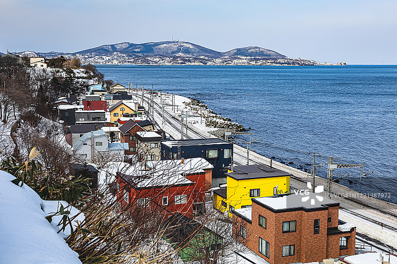 日本北海道小taru的Asari，石kari湾和太平洋沿岸被雪覆盖的五颜六色的房子图片素材