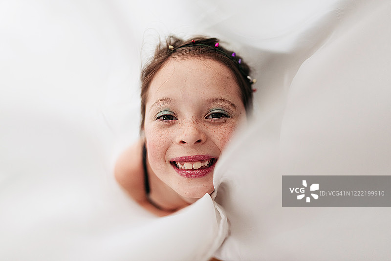 一个化妆的小女孩的肖像裹在窗帘里图片素材