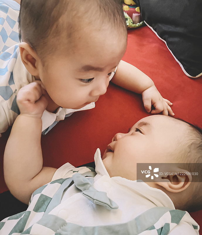 双胞胎中国男婴刚刚醒来，微笑着互相玩耍图片素材