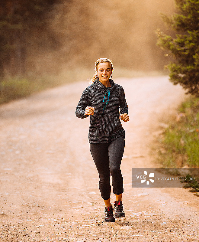 健康快乐的女人在一条土路上奔跑图片素材