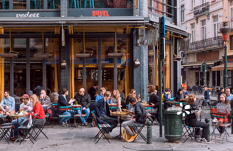 一群快乐的人在繁忙的晚上聚集在街头的咖啡馆区喝酒图片素材