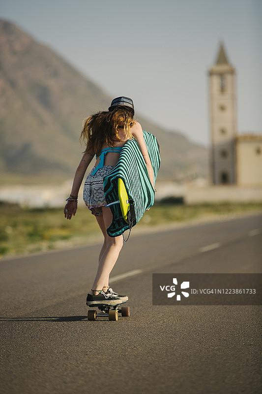 后视图的年轻女子与滑板在柏油路，阿尔梅里亚，西班牙图片素材