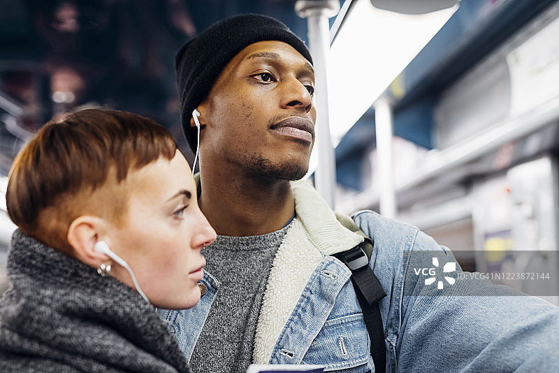 一对年轻夫妇在地铁上共用耳机图片素材