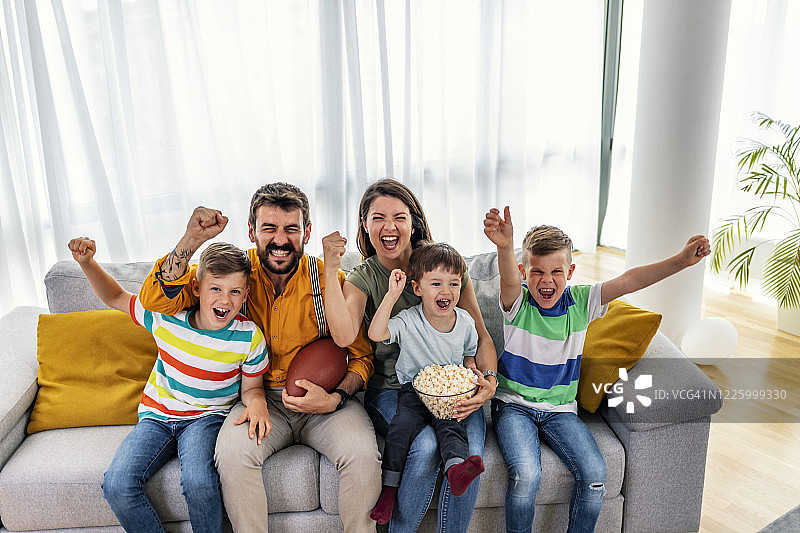 在家里看电视转播的橄榄球比赛时，一家人欢呼雀跃图片素材
