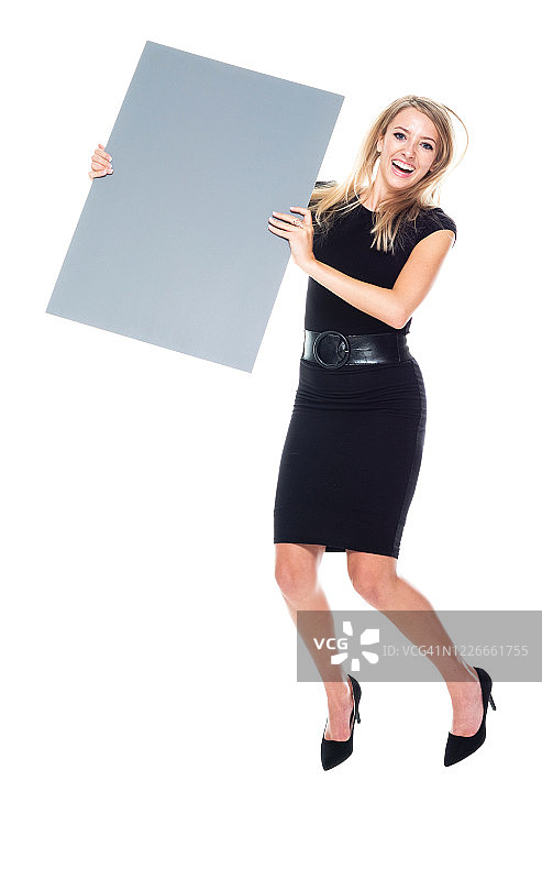 白人女商人身穿商务服装，举着横幅标语，在白色背景前跳跃图片素材