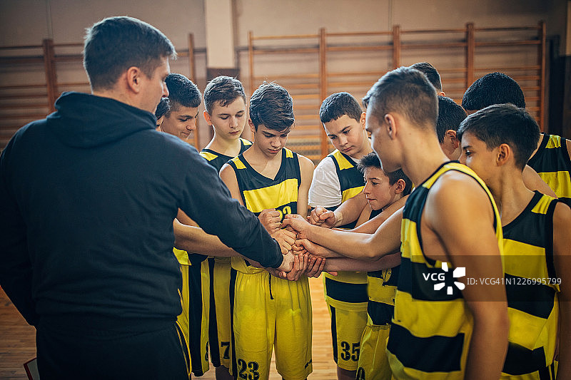 十几岁的男孩篮球队和教练牵手比赛后图片素材