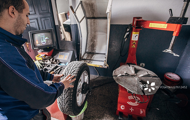 男机械师更换轮胎和平衡它图片素材