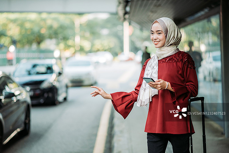 亚洲年轻的马来女游客在公共交通站挥手叫出租车图片素材