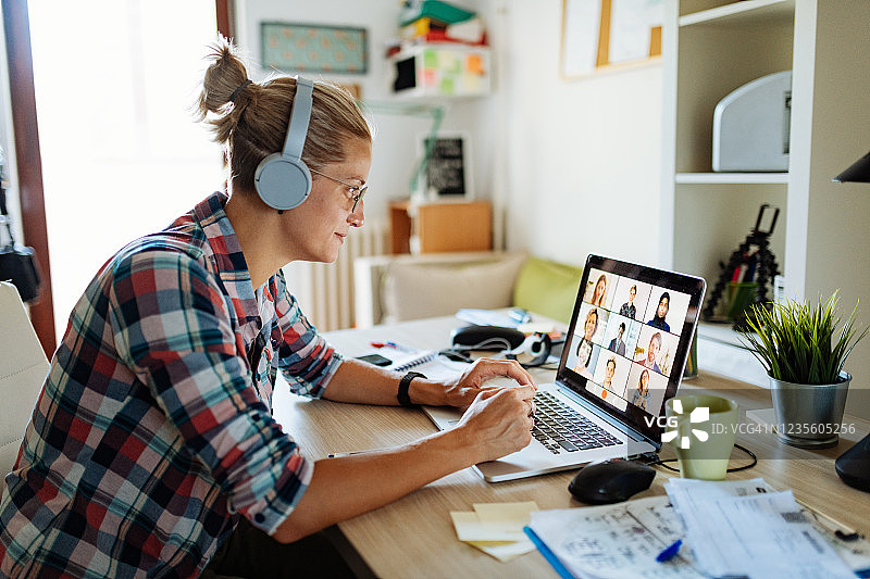 专业的女商人在家里使用笔记本电脑进行视频通话和远程办公图片素材