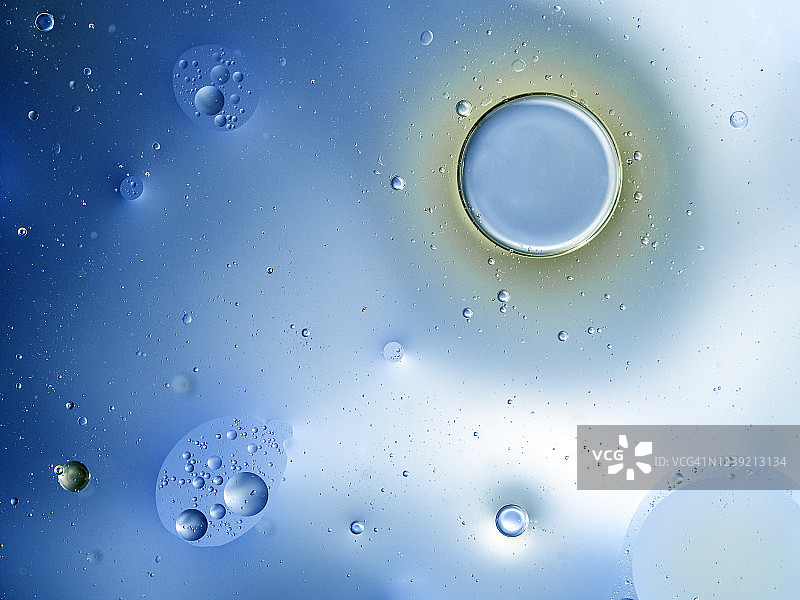 由蓝色液体背景上的气泡和水滴构成的抽象形状和纹理的完整框架。图片素材