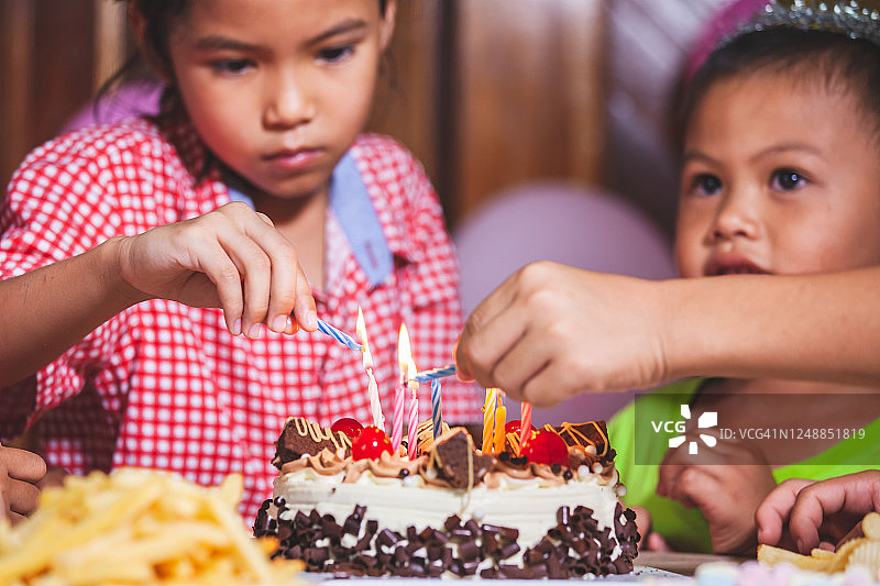 亚洲儿童女孩和男孩一起在生日蛋糕上点燃蜡烛图片素材