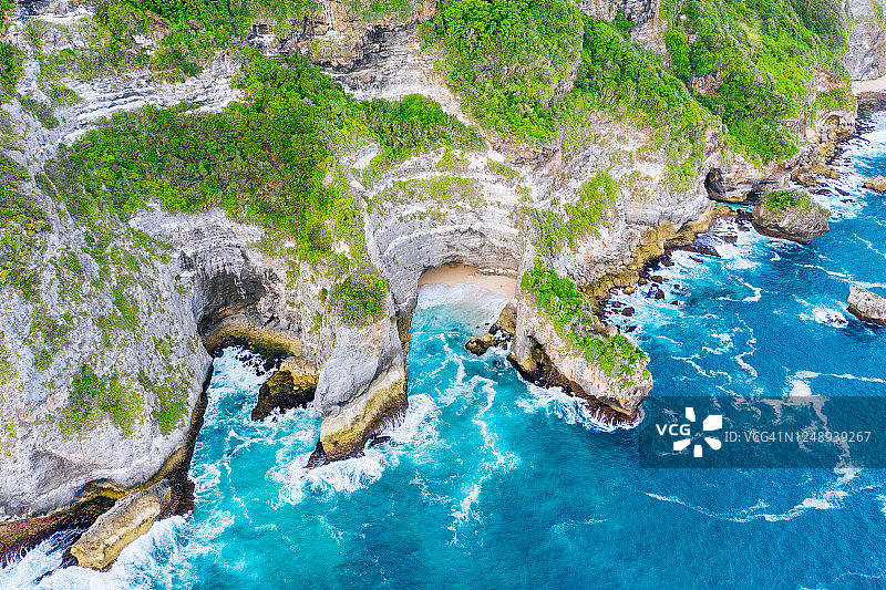 蓝色的海洋和被热带植物覆盖的悬崖。从上面看巴厘岛海岸。空中无人机拍摄。图片素材