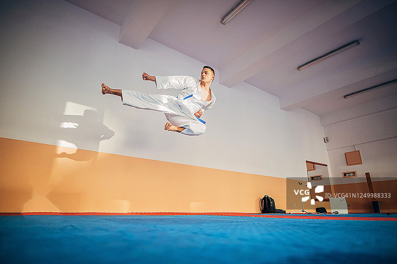 年轻的男空手道学生在半空中做跳踢图片素材