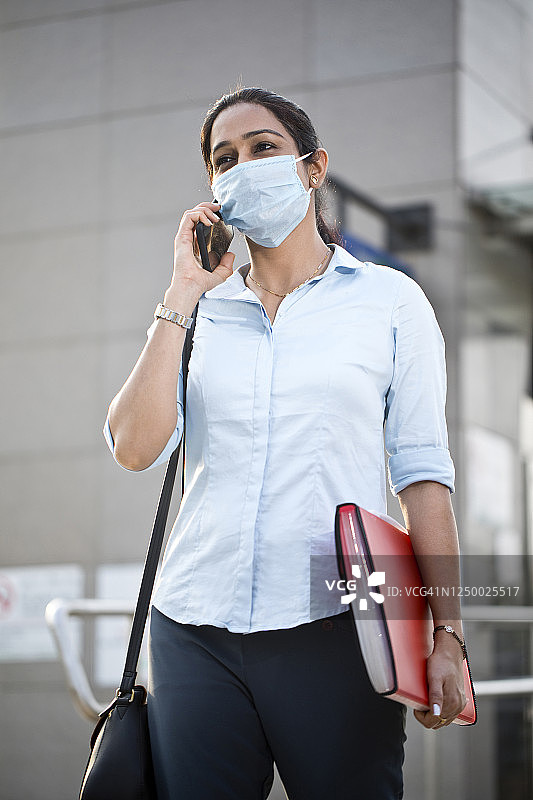 女商人戴着口罩在城市里使用手机图片素材
