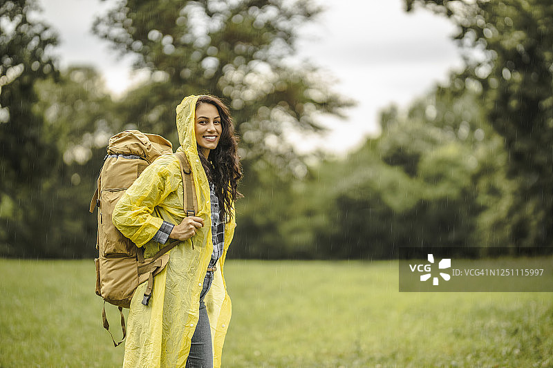 年轻女子穿着防水夹克在雨中徒步旅行图片素材