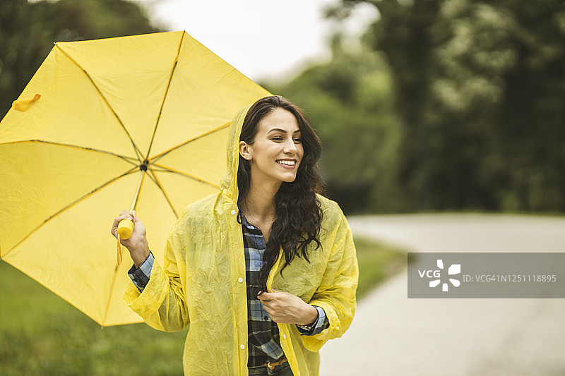 拿着黄伞，穿着黄雨衣，享受着雨的女人图片素材