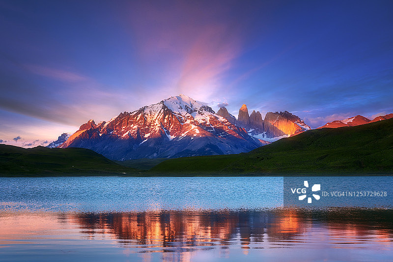 第一缕阳光照亮了潘恩马西夫的山峰，它的倒影映在阿玛加湖的水面上图片素材