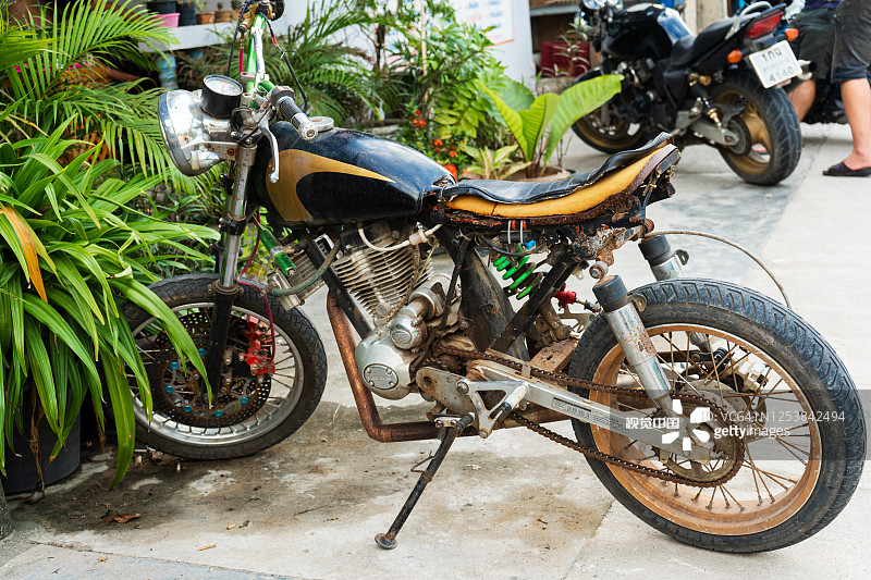 旧摩托车。这是亚洲最典型的汽车。一辆破旧的摩托车停在咖啡馆附近的停车场图片素材