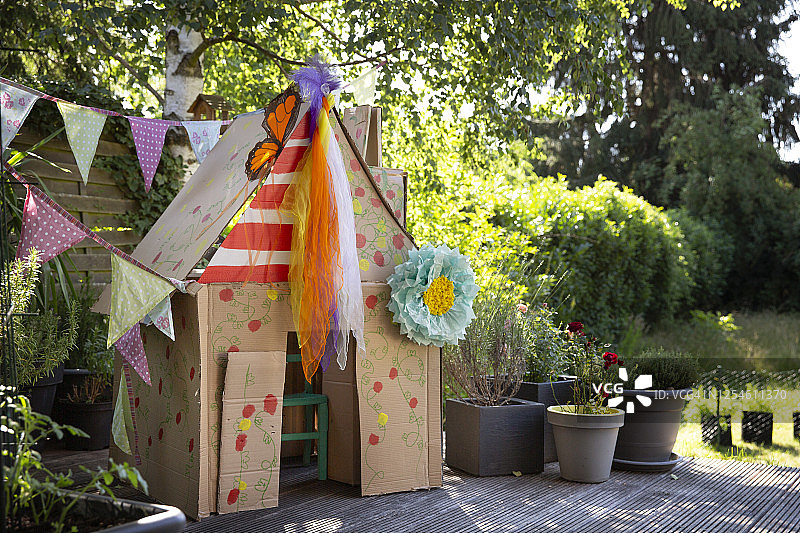 在后院，用回收的纸板箱制作的彩色儿童自制玩具屋图片素材