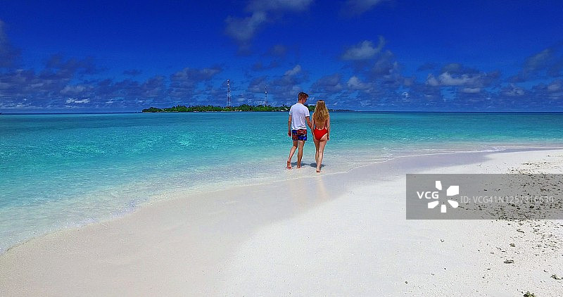 在马尔代夫，一对游客夫妇喜欢手牵着手在美丽干净的海滩上散步图片素材