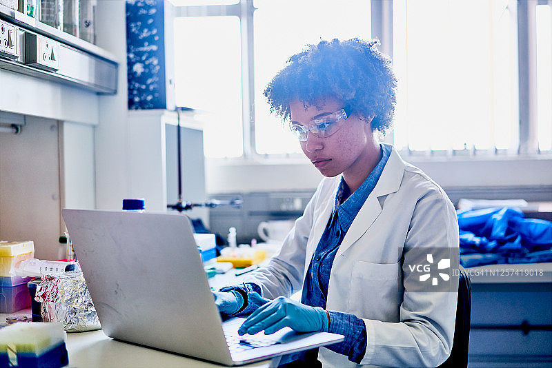 一名年轻科学家在实验室书桌前用笔记本电脑工作图片素材