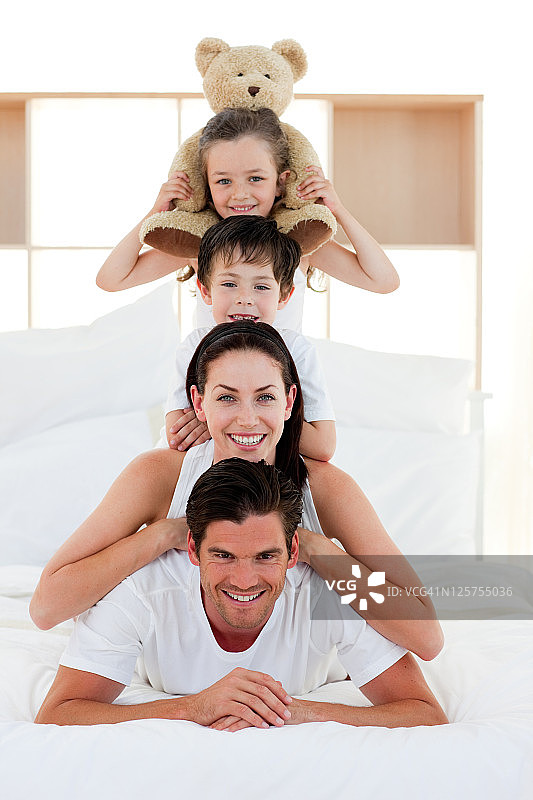 年轻的家庭一起在床上玩耍图片素材