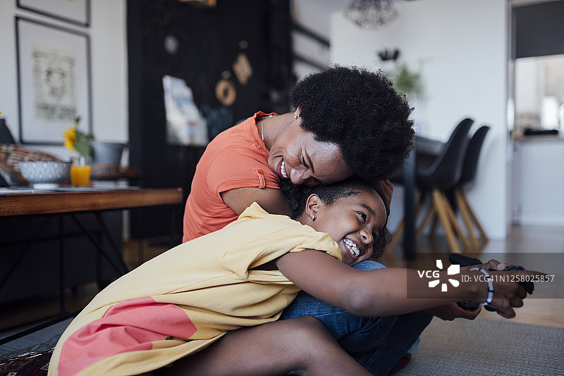 一个快乐的非裔美国母亲和女儿在家里一起玩电子游戏图片素材