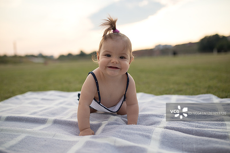 微笑的女婴在公园里爬行图片素材