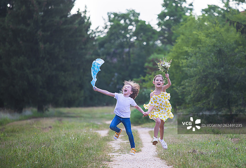 两个孩子捧着一束野花在公园里奔跑图片素材