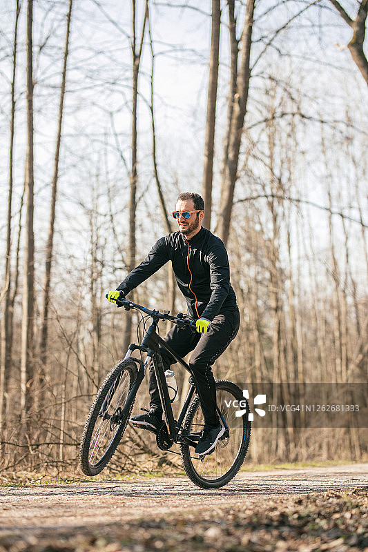 男性山地自行车穿过森林图片素材