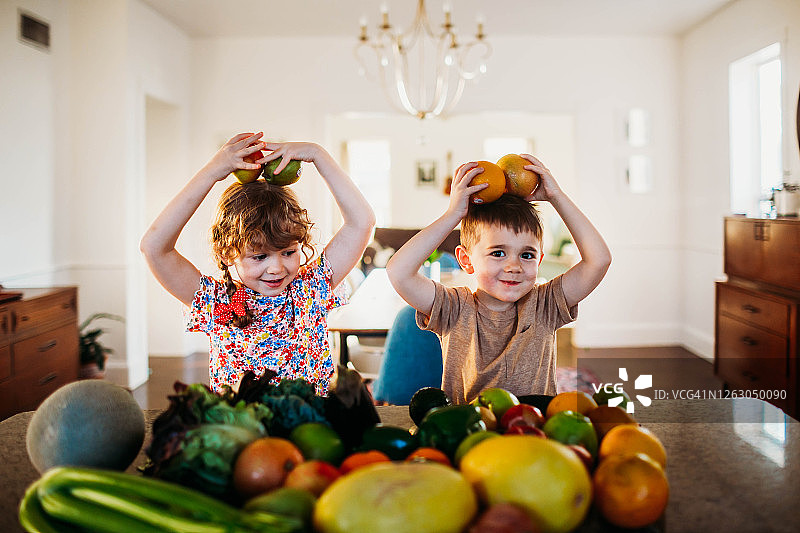 小男孩和小女孩坐在厨房柜台前玩水果图片素材