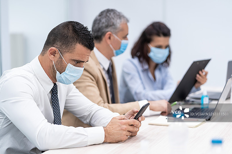 办公室里戴医用口罩的同事，新冠肺炎期间的新工作规则图片素材