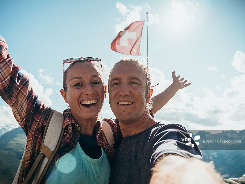 夫妇在山顶上举着瑞士国旗自拍图片素材