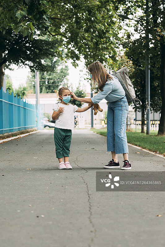 新常态:母亲和女儿戴防护口罩一起上学，冠状病毒预防理念图片素材