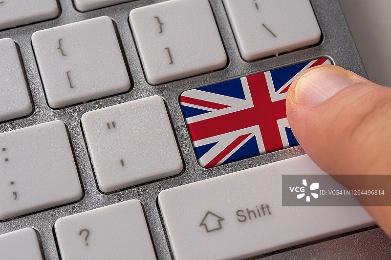 男性的手按着键盘上有英国国旗的按钮。网上国际经营理念。图片素材