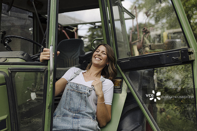一个快乐的年轻女人在乡间的拖拉机旁图片素材