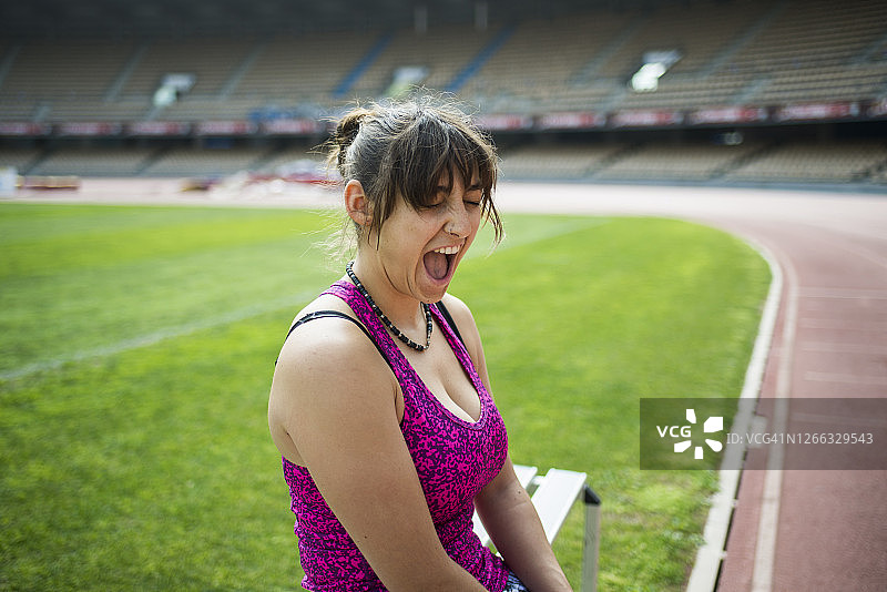 微笑的女运动员在体育场休息图片素材