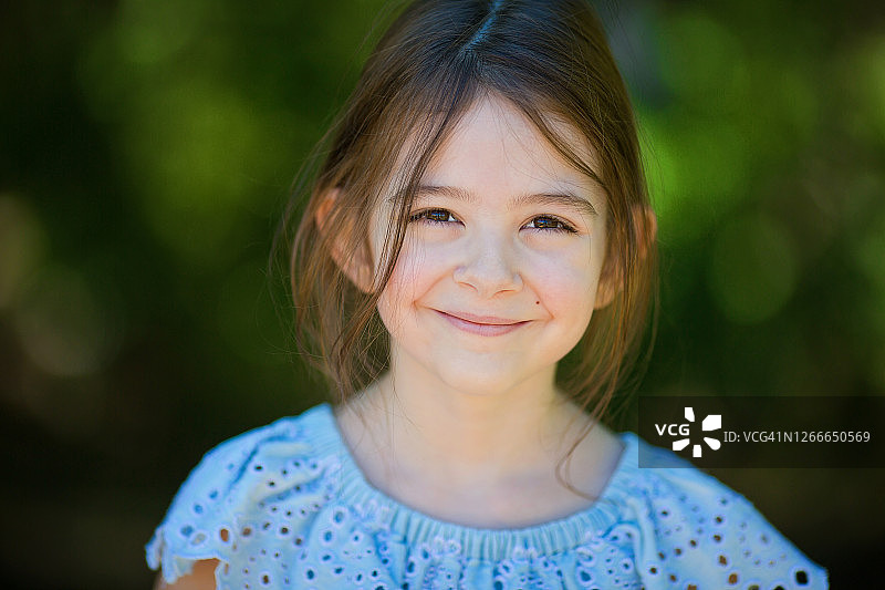 可爱的小女孩在森林里微笑着看着相机的特写图片素材