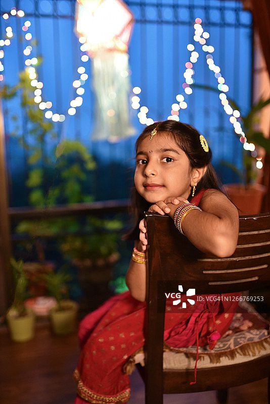 在排灯节期间，一个女孩在印度传统服装坐在椅子上的肖像图片素材
