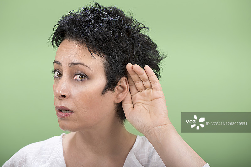 成年女人听不到什么，就把手放在耳朵后面。图片素材