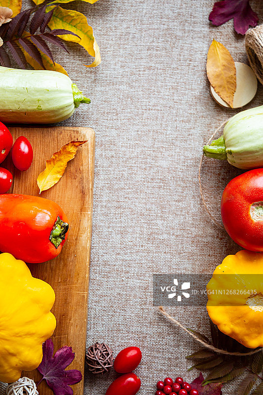 由南瓜、树叶、番茄和南瓜在米色背景上组成的喜庆的秋天。图片素材