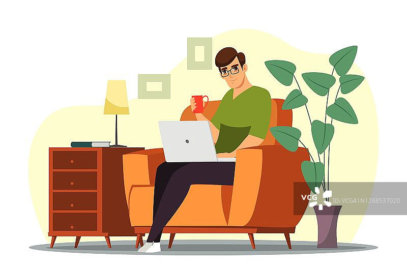 一个男人坐在椅子上，拿着笔记本电脑，在家里的办公室喝咖啡图片素材