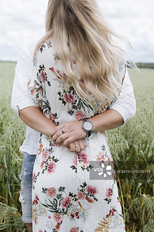 爱的丈夫拥抱年轻的女人站在燕麦地里图片素材