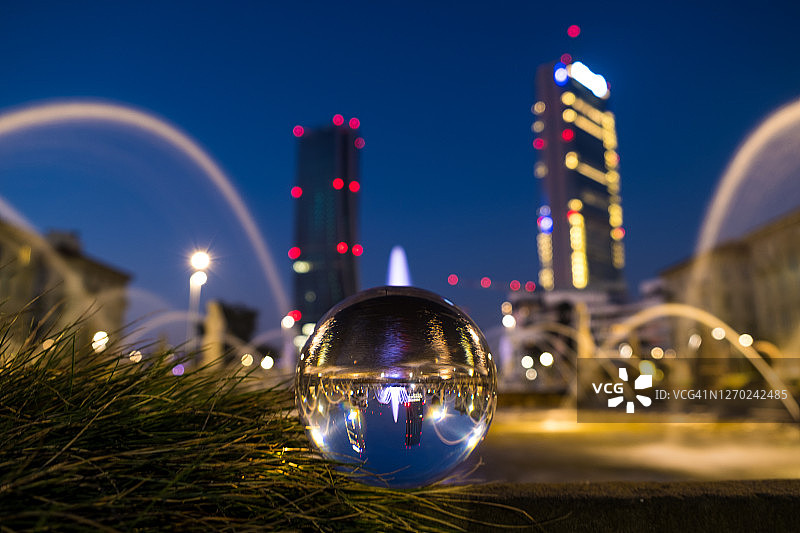 透明球体上方的喷泉与米兰现代建筑的夜晚灯光图片素材