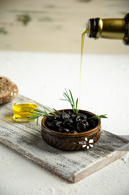 橄榄和橄榄油瓶子放在质朴的白色桌子上图片素材
