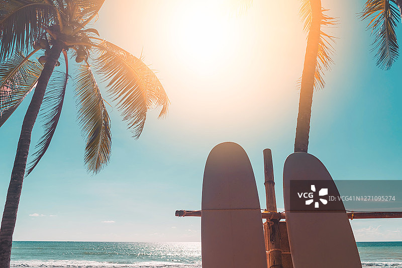 冲浪板和棕榈树在日落天空抽象的背景。暑假与运动极限概念。图片素材