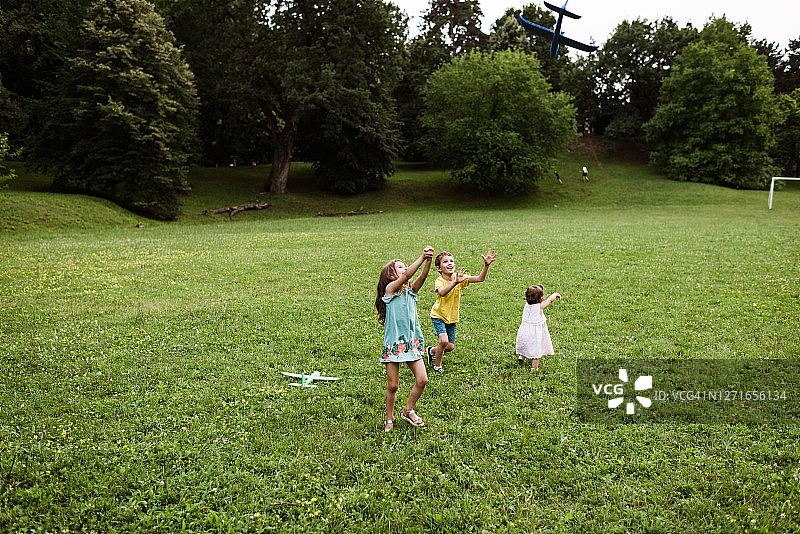 孩子们在田野里玩飞机玩具图片素材