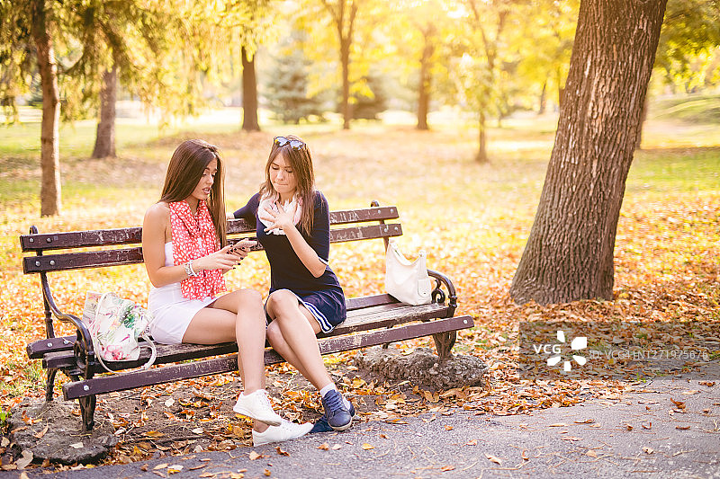 女性朋友在长椅上聊天和打电话图片素材